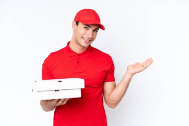 Pizza teslimatı, iş üniformalı beyaz arka planda izole edilmiş pizza kutuları alan beyaz bir adam. Davet edildiği için ellerini yana uzatıyor.