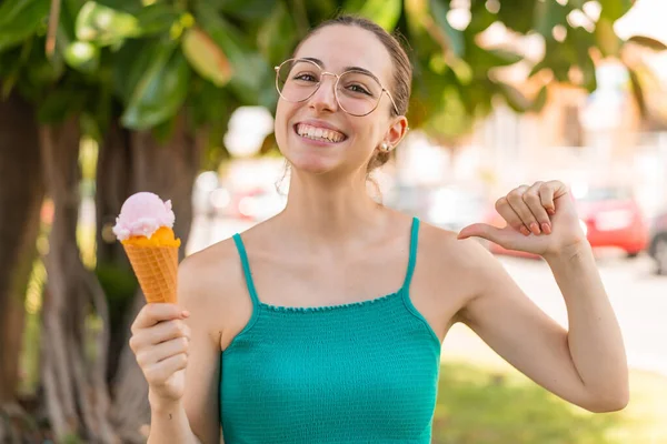 Young pretty woman with a cornet ice cream at outdoors proud and self-satisfied
