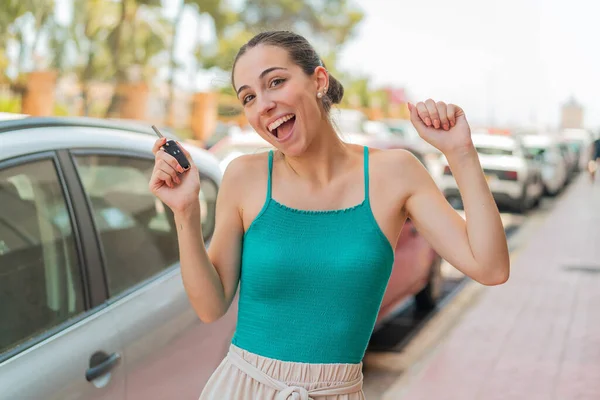 車のキーを保持し 勝利を祝う屋外で若い美しい女性 — ストック写真