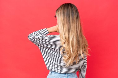 Genç Uruguaylı kadın kırmızı arka planda izole edilmiş ve düşünüyor.