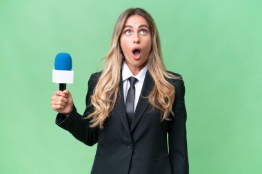 Genç, güzel Uruguaylı televizyon sunucusu izole edilmiş arka planda yukarı bakıyor ve şaşırmış bir ifadeyle