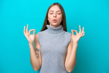 Genç Litvanyalı kadın Zen pozunda mavi arka planda izole edilmiş.