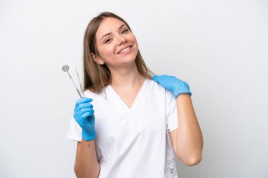 Beyaz arka planda izole edilmiş aletleri tutan dişçi kadın gülüyor.