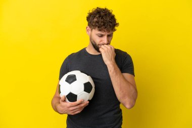 Yakışıklı genç futbolcu sarı arka planda izole edilmiş şüpheleri var.
