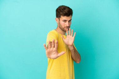 Beyaz tenli yakışıklı adam mavi arka planda izole edilmiş gergin eller öne uzanıyor.