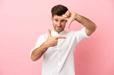 Pembe arka planda izole edilmiş, odaklanmış, beyaz, yakışıklı bir genç. Çerçeve sembolü