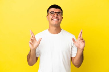 Genç yakışıklı, izole edilmiş sarı arka planda, şans diliyor ve en iyisini diliyor.