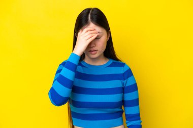 Sarı arka planda başağrısı olan genç Çinli bir kadın.