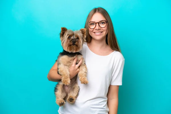 Young Lithuanian woman holding a dog isolated on blue background smiling a lot