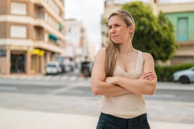 Açık havada, kafası karışmış genç sarışın bir kadın.