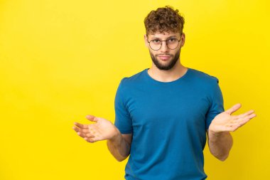 Sarı arka planda izole edilmiş yakışıklı beyaz bir adam. Şüpheleri var.