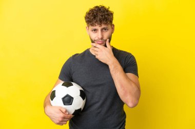 Yakışıklı genç futbolcu. Sarı arka planda izole edilmiş.