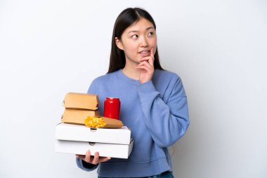 Beyaz arka planda hazır yemek tutan genç Çinli kadın yukarı bakarken bir fikir düşünüyor.