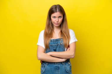 Sarı arka planda izole edilmiş genç beyaz kadın üzgün hissediyor.