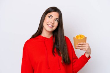 Patates kızartması yakalayan genç Brezilyalı kadın beyaz arka planda izole edilmiş gülümserken yukarı bakıyor.