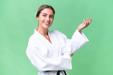 Genç Uruguaylı kadın izole edilmiş arka planda karate yapıyor. Davet etmek için ellerini yana uzatıyor.