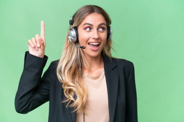 Tele pazarlamacı güzel Uruguaylı kadın tecrit edilmiş bir arka planda çalışan bir kulaklıkla çözümü anlamaya çalışırken parmağını kaldırıyor.