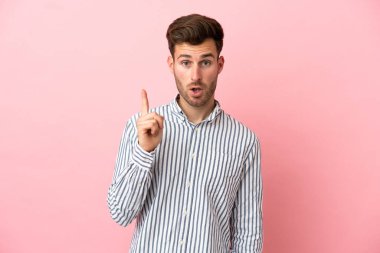 Pembe arka planda soyutlanmış beyaz, yakışıklı bir adam çözümü bulmak için parmağını kaldırıyor.