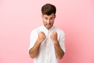 Pembe arka planda izole edilmiş beyaz, yakışıklı genç bir adam kötü bir durum yüzünden hayal kırıklığına uğradı.