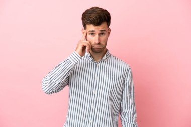 Pembe arka planda izole edilmiş beyaz, yakışıklı bir adam bir fikir düşünüyor.