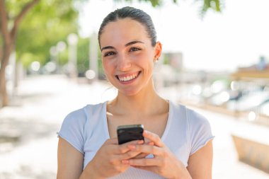 Dışarıdaki güzel bayan cep telefonuyla mesaj yolluyor.