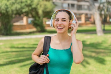 Açık havada müzik dinleyen genç ve güzel bir kadın.