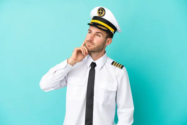 stock image Airplane caucasian pilot isolated on blue background thinking an idea while looking up