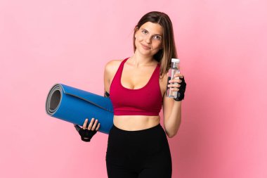 Pembe arka planda izole edilmiş genç Slovak kadın spor su şişesi ve bir paspas ile
