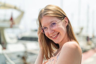 Açık havada gözlüklü genç bir Fransız kız Neşeli bir ifadeyle