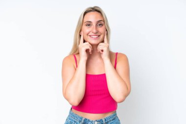 Beyaz arka planda izole edilmiş genç beyaz kadın mutlu ve hoş bir ifadeyle gülümsüyor.