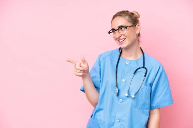 Pembe arka planda izole edilmiş genç bir cerrah kadın parmak göstererek bir ürün sunuyor.