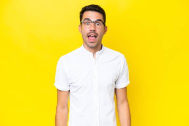 Sürpriz yüz ifadesi ile izole sarı arka plan üzerinde genç yakışıklı adam