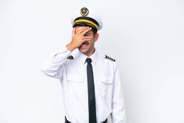 Airplane pilot over isolated white background covering eyes by hands and smiling