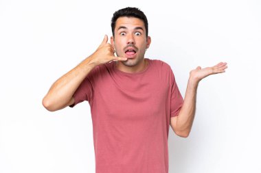 Soyutlanmış beyaz arka planda genç yakışıklı bir adam telefon jesti yapıyor ve şüpheci