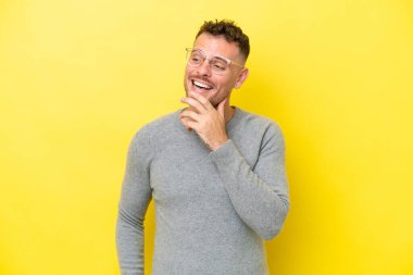 Beyaz tenli yakışıklı adam sarı arka planda izole edilmiş gülümserken yukarı bakıyor.