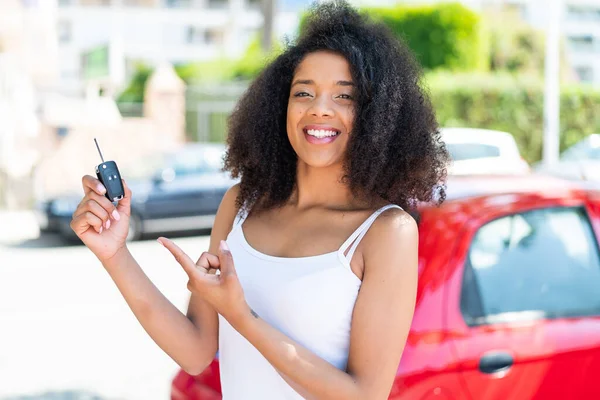 若いアフリカ系アメリカ人女性が屋外で車の鍵を握り それを指摘する — ストック写真