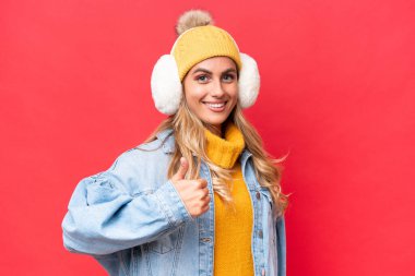 Genç, güzel Uruguaylı bir kadın kırmızı arka planda izole edilmiş kışlık kuklalar takıyor.