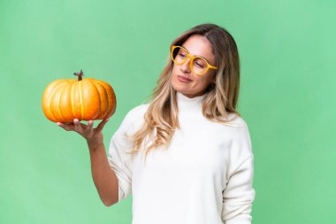 Genç Uruguaylı bir kadın kabağı izole edilmiş bir arka planda hüzünlü bir ifadeyle tutuyor.