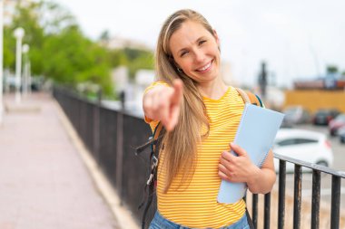 Açık havadaki genç sarışın bayan kendine güvenen bir ifadeyle seni işaret ediyor.