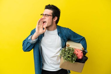 Rus adam sarı arka planda izole edilmiş şeylerle dolu bir kutuyu kaldırırken hareket ediyor ve ağzı sonuna kadar açık bağırıyor.