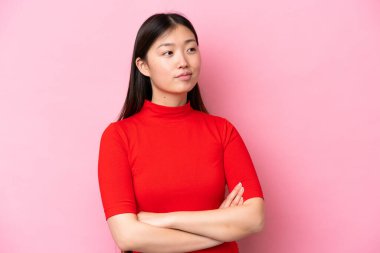 Pembe arka planda izole edilmiş genç Çinli kadın yan tarafa bakıyor.