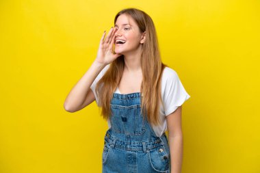 Sarı arka planda izole edilmiş genç beyaz kadın ağzı sonuna kadar açık bağırıyor.