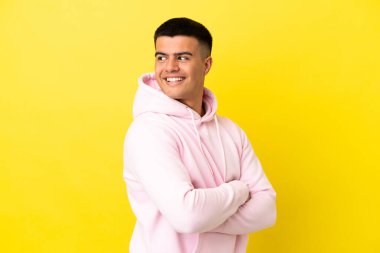 Kolları geçti ve mutlu izole sarı arka plan üzerinde genç yakışıklı adam