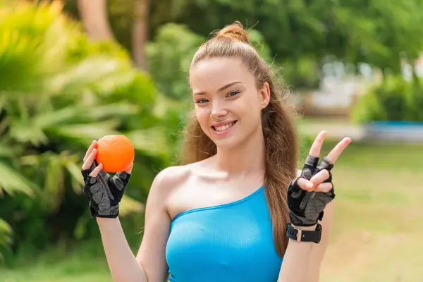 Joven Chica Bastante Deportivo Sosteniendo Una Naranja Aire Libre Sonriendo —  Fotos de Stock