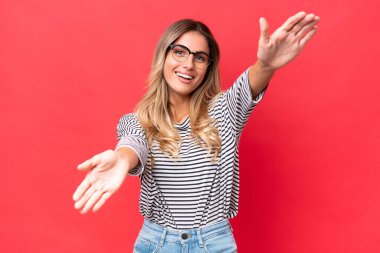 Genç Uruguaylı kadın kırmızı arka planda izole edilmiş sunar ve davet edilir.