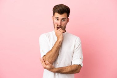 Pembe arka planda izole edilmiş beyaz, yakışıklı genç adam sağa bakarken şaşırmış ve şok olmuştu.