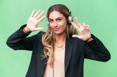 Tele pazarlamacı güzel Uruguaylı kadın tecrit edilmiş arka planda kulaklıkla çalışıyor. Parmaklarıyla sekiz kişi sayıyor.