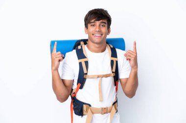 İzole edilmiş beyaz arka planı olan büyük bir sırt çantasıyla genç dağcı kadın harika bir fikre işaret ediyor.