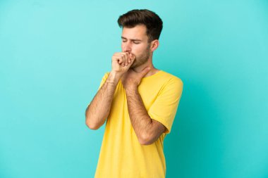 Kafkasyalı yakışıklı genç adam mavi arka planda izole edilmiş, çok öksürüyor.