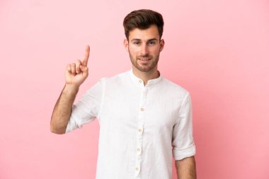 Pembe arka planda izole edilmiş beyaz, yakışıklı genç adam harika bir fikre işaret ediyor.